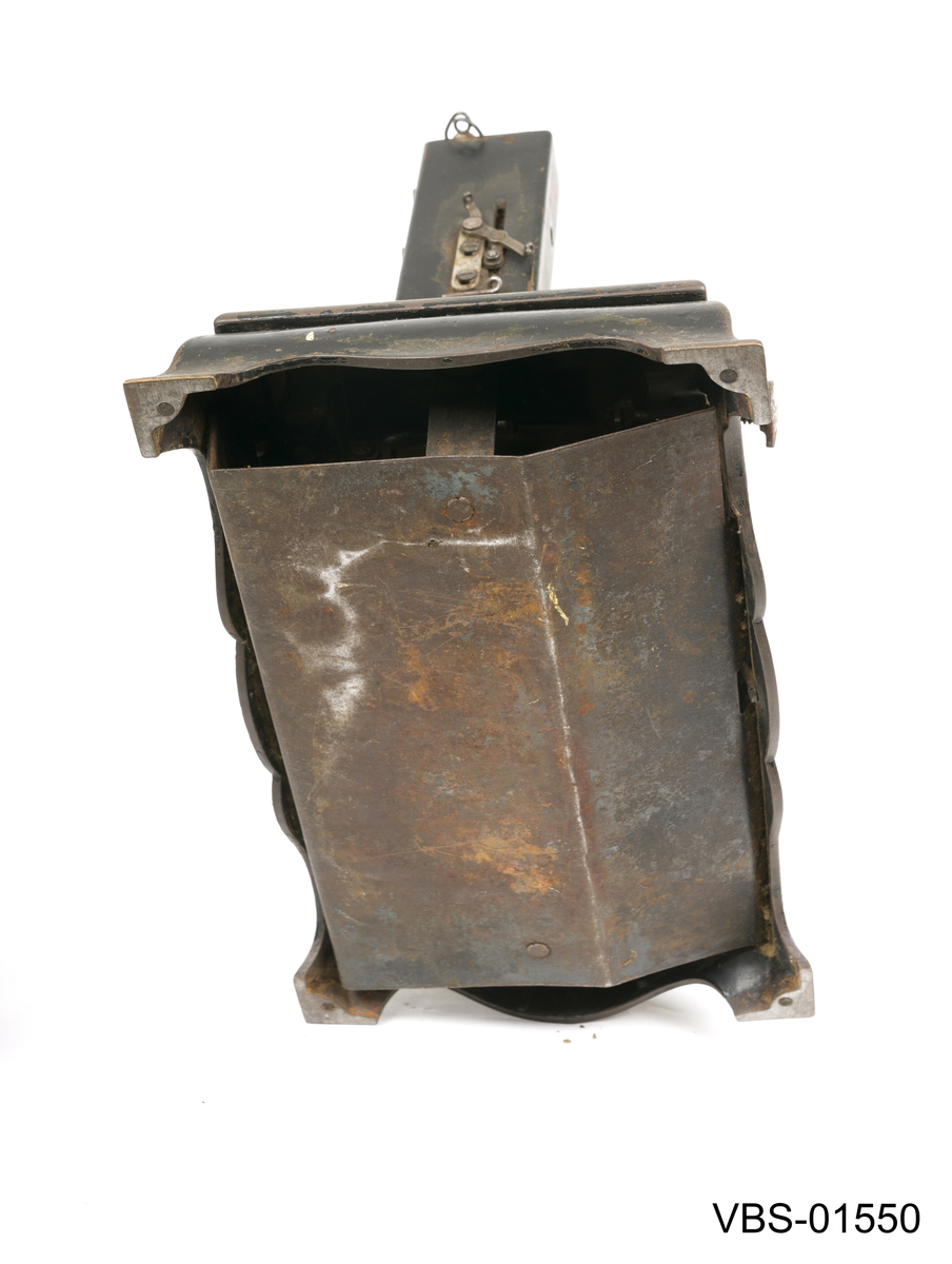 Symaskin med sveiv i svart jern. Den er festet med to hensgler på en solid sokkel av 6 cm i støpejern.   
Muligens produsert av GROVEN & BAKER (Boston, USA), produsenter siden 1851.