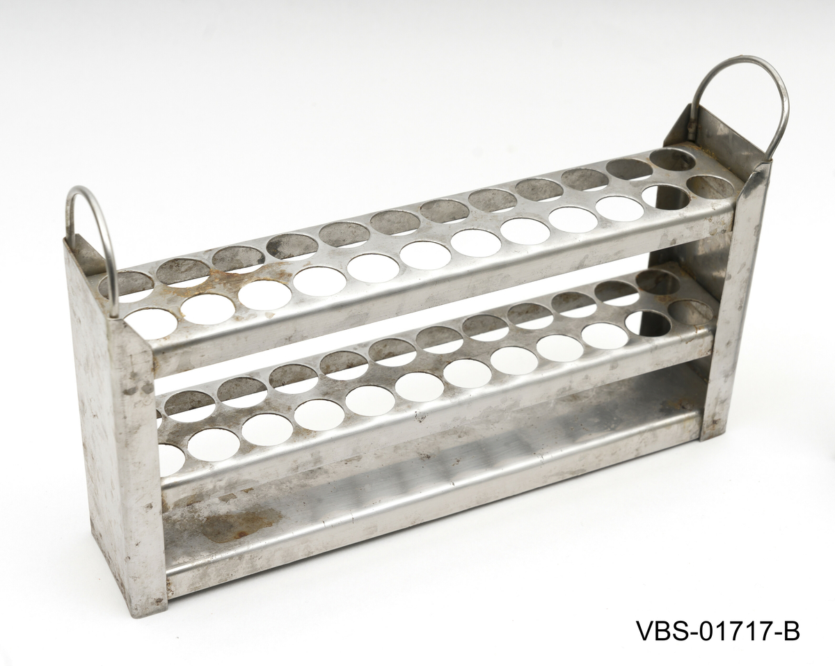 Aluminiums eske med, uten lokk, og to håndtak. Den inneholder et metallstativ med flere reagensrørholder eller glassrør.
Aluminiums eske (A), stål stativ (B) og glassrør (C) på bilder.

Glassrør settet består av: 
2 hvite glass prøverør (13x2cm diameter). Brukte.
3 grønne glassrør (20x1,5 cm diameter). Brukte.
5 hvite glassrør (28x1,5 cm diameter). Brukte.
3 hvite glassrør (50x1,5 cm diameter). Brukte.
4 nye hvite glassrør (28x1,5 cm diameter). Brukte.