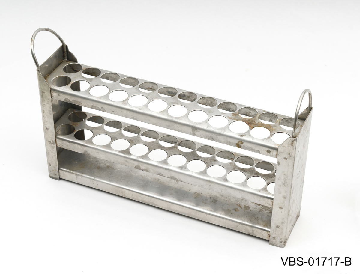 Aluminiums eske med, uten lokk, og to håndtak. Den inneholder et metallstativ med flere reagensrørholder eller glassrør.
Aluminiums eske (A), stål stativ (B) og glassrør (C) på bilder.

Glassrør settet består av: 
2 hvite glass prøverør (13x2cm diameter). Brukte.
3 grønne glassrør (20x1,5 cm diameter). Brukte.
5 hvite glassrør (28x1,5 cm diameter). Brukte.
3 hvite glassrør (50x1,5 cm diameter). Brukte.
4 nye hvite glassrør (28x1,5 cm diameter). Brukte.
