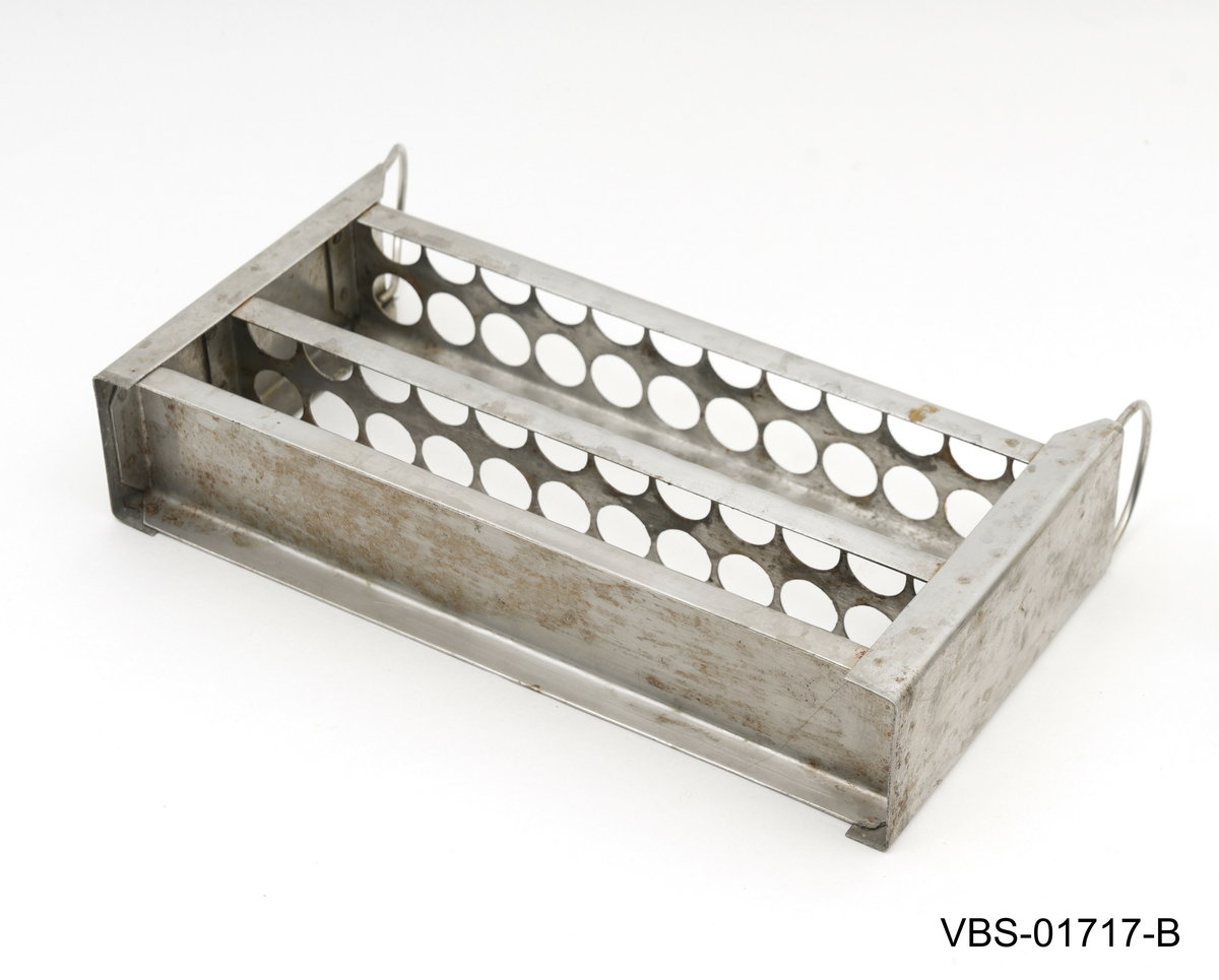 Aluminiums eske med, uten lokk, og to håndtak. Den inneholder et metallstativ med flere reagensrørholder eller glassrør.
Aluminiums eske (A), stål stativ (B) og glassrør (C) på bilder.

Glassrør settet består av: 
2 hvite glass prøverør (13x2cm diameter). Brukte.
3 grønne glassrør (20x1,5 cm diameter). Brukte.
5 hvite glassrør (28x1,5 cm diameter). Brukte.
3 hvite glassrør (50x1,5 cm diameter). Brukte.
4 nye hvite glassrør (28x1,5 cm diameter). Brukte.