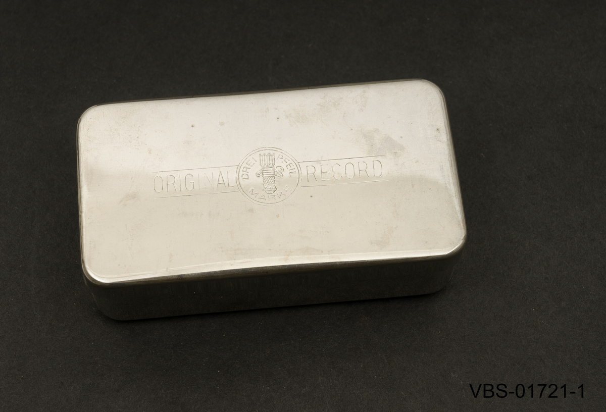 5ml sprøyte med beholder som ligger demontert i to deler, sammen med 3 sprøytespisser (nr. 12) og en stålsonde for å rengjøre nålen på innsiden.
Beholderen er en metallboks/etui i rusfritt stål med et stempel på lokket.