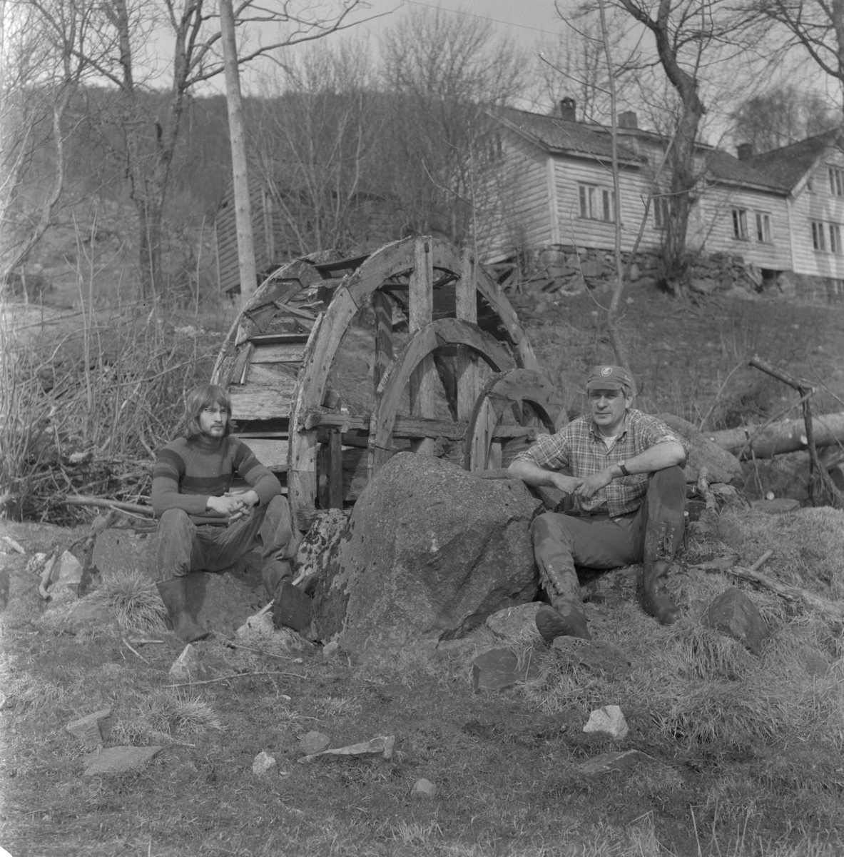 Det gamle vasshjulet i Bjordal i Vikebygd, 1977. I bakgrunnen Gamletunet. I forgrunnen, frå venstre: Andor Bjordal og Dominicus Bjordal.