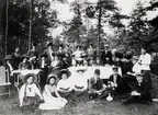 Ett sällskap i olika åldrar har slagit sig ner vid några kaffebord på Kvarnhagen, Växjö, 1910.