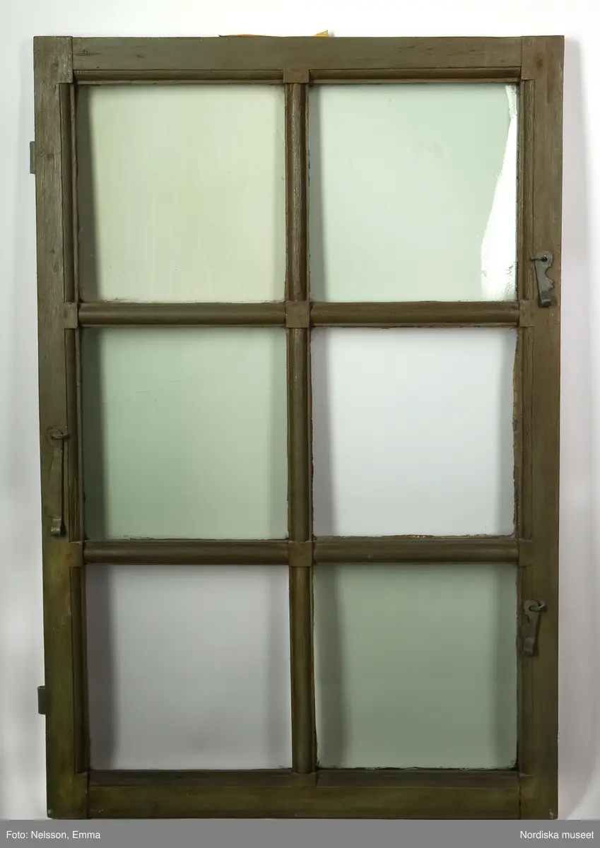 Fönster med karm, fyra fönsterbågar med vardera sex glasrutor, omkring 1740. Utvändigt målat brunt, invändigt grågrön oljefärg. 

Utåtgående fönsterbåge. Träspröjsar med en på insidan rundad vulst som möts i kvadratiskt spröjskryss. Bågens yttersida förstärkt med hörnjärn av 1700-talstyp. Fönsterkarm av furu med symmetrisk korspost. Fönsterbleck av målad plåt, fäst i karmens nederkant. Med fönsterbräda. Beslag för hängning av fönsterluckor. Gångjärn, uppställnings- och stängningsbeslag.  

Anm: Partiellt färgbortfall och skador. Ett av tre fönster, placerat på rummets långsida, mot gatan.
/Anna Arfvidsson Womack 2021-07-14