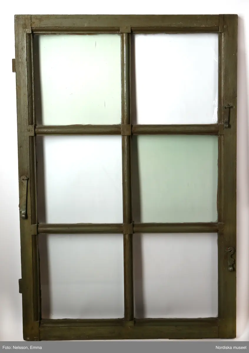 a-d) Fönster med e) karm, fyra fönsterbågar med vardera sex glasrutor, omkring 1740. Utvändigt målat brunt, invändigt grågrön oljefärg. 

Utåtgående fönsterbåge. Träspröjsar med en på insidan rundad vulst som möts i kvadratiskt spröjskryss. Bågens yttersida förstärkt med hörnjärn av 1700-talstyp. Fönsterkarm av furu med symmetrisk korspost. Fönsterbleck av målad plåt, fäst i karmens nederkant. Med fönsterbräda. Beslag för hängning av fönsterluckor. Gångjärn, uppställnings- och stängningsbeslag.  

Anm: Partiellt färgbortfall och skador. Ett av tre fönster(NM.0334543-NM.0334545), placerat på rummets långsida, mot gatan.
/Anna Arfvidsson Womack 2021-07-14