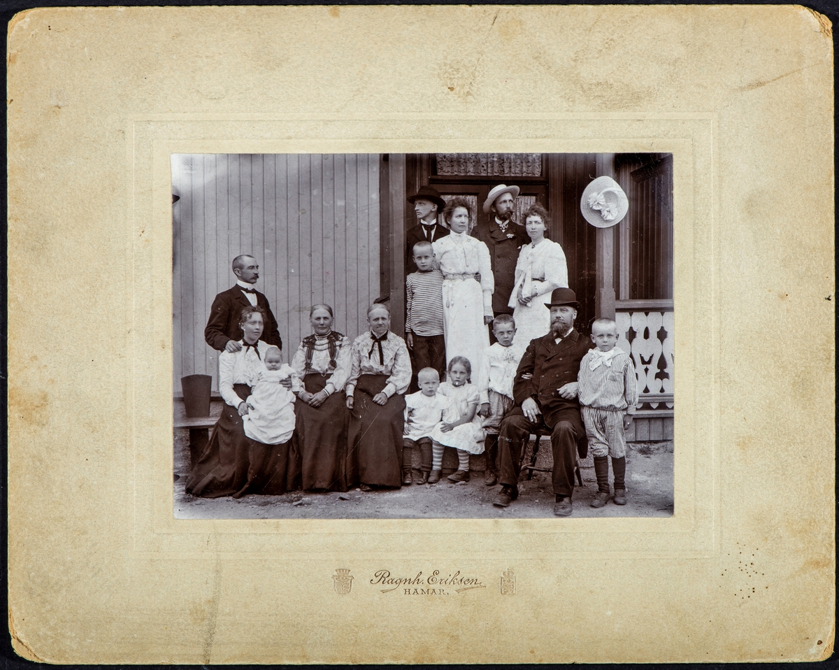 Hamar, skreddermester Johan Eriksen med familie, gruppe 15 personer. Fra venstre : lærer Amund Gulden (1873-), foran sitter kona lærer Laura Gulden født Eriksen (1873-), med datter Hjørdis på fanget. Så 2 ukjente damer, liten gutt: Jens (???), Marta Melhus, Reidar Sannerud (1898-), Skreddermester Johan Eriksen (1840-1916) og Erling Sannerud. 
Bak: Erling ( ? ), Marie Sannerud, Otto ( ? ) , Betzy ( ? ) , Jan ( ? ),