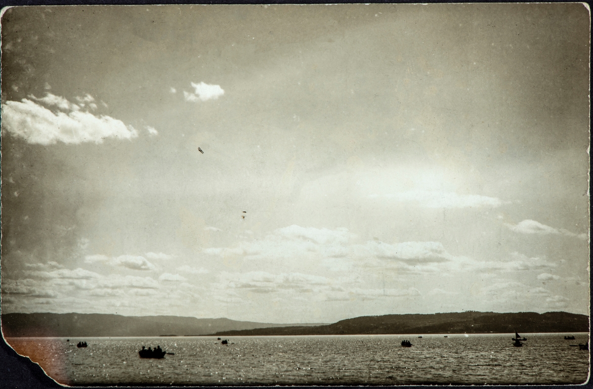 Fritjof Løberg hopper ut av et fly, med fallskjerm over Mjøsa. Hamar. Båter