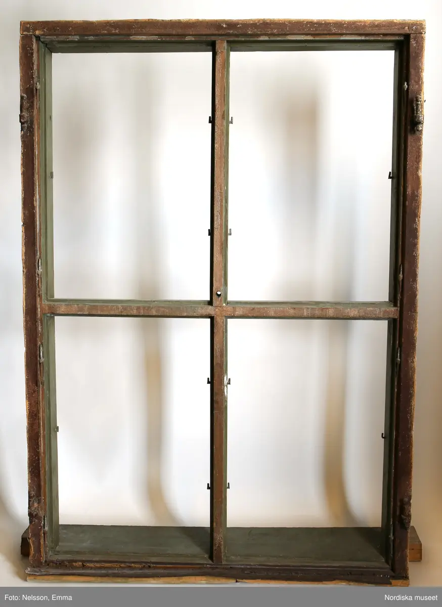 a-d) Fönster med e) karm, fyra fönsterbågar med vardera sex glasrutor, omkring 1740. Utvändigt målat brunt, invändigt grågrön oljefärg. 

Utåtgående fönsterbåge. Träspröjsar med en på insidan rundad vulst som möts i kvadratiskt spröjskryss. Bågens yttersida förstärkt med hörnjärn av 1700-talstyp. Fönsterkarm av furu med symmetrisk korspost. Fönsterbleck av målad plåt, fäst i karmens nederkant. Med fönsterbräda. Beslag för hängning av fönsterluckor. Gångjärn, uppställnings- och stängningsbeslag.  

Anm: Partiellt färgbortfall och skador. Ett av tre fönster(NM.0334543-NM.0334545), placerat på rummets långsida, mot gatan.
/Anna Arfvidsson Womack 2021-07-14