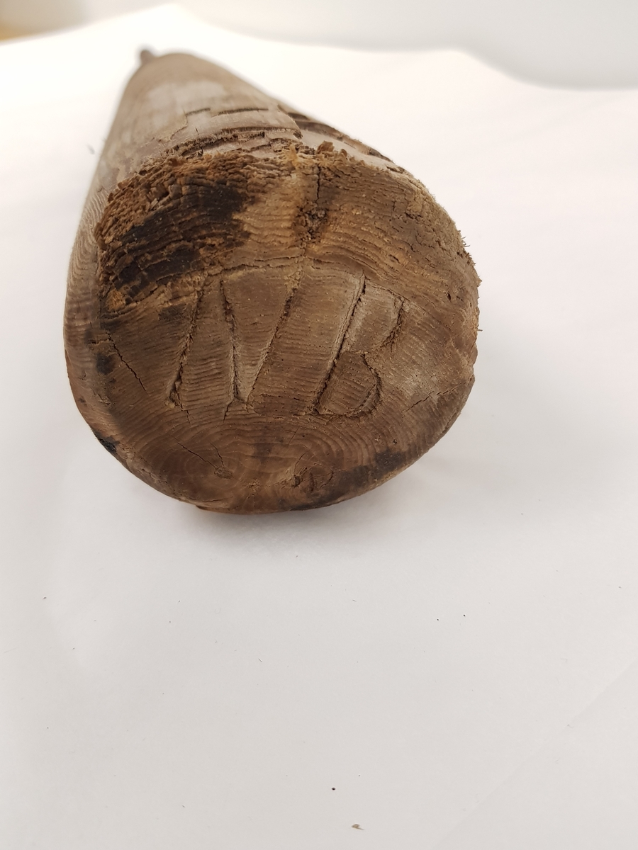 Et dreid trestykke med en jernstang festet i et hull i den avsmalende enden