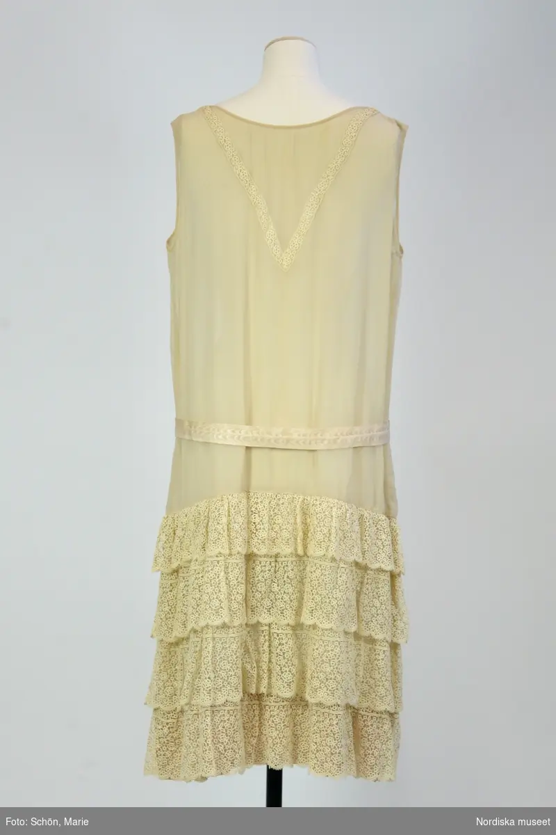 Ordered by Kerstin Stafsing née Jonsson (1899–1986). Delivered ca. 1925. Chiffon evening dress with lace flounces and a mother 
of pearl belt buckle in the shape of an owl’s head. Possibly after an original by Coco Chanel.