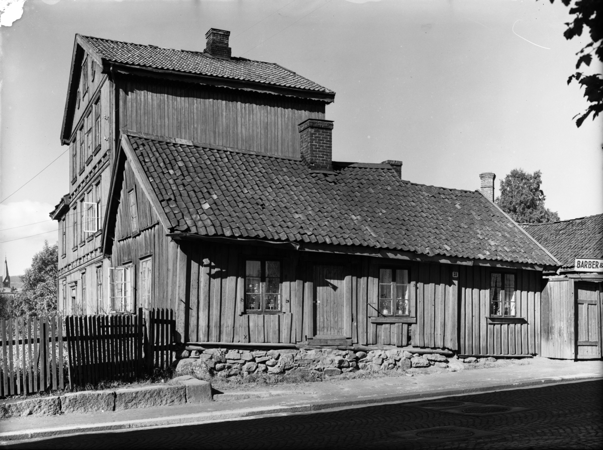 Forfallen trebygning, sannsynligvis Sagene kirke i bakgrunnen. Skilt: Barberer