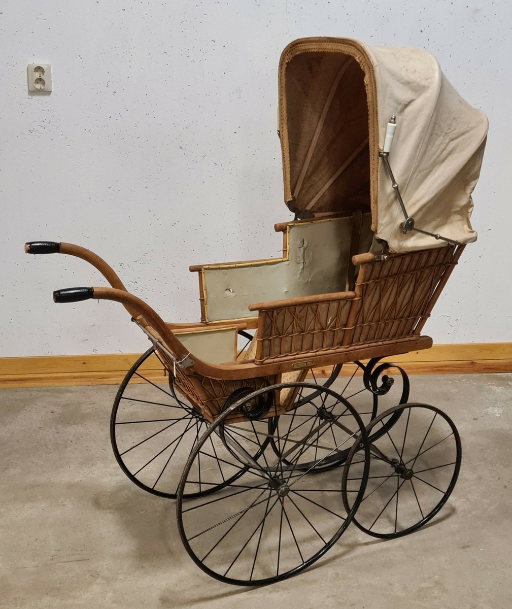 Barnvagn med funktion av både liggvagn och sittvagn. Sufflett. Vagnen i flätad rotting. Liggyta: 75 x 40 cm, Framhjul diam: 39 cm. Bakhjul diam: 55 cm.

Barnvagnen stod på vinden när Gilbert Larssons föräldrar köpte huset Södergatan 22.

Har troligen tillhört några hyresgäster som bebott fastigheten mellan åren 1917 - 1931.