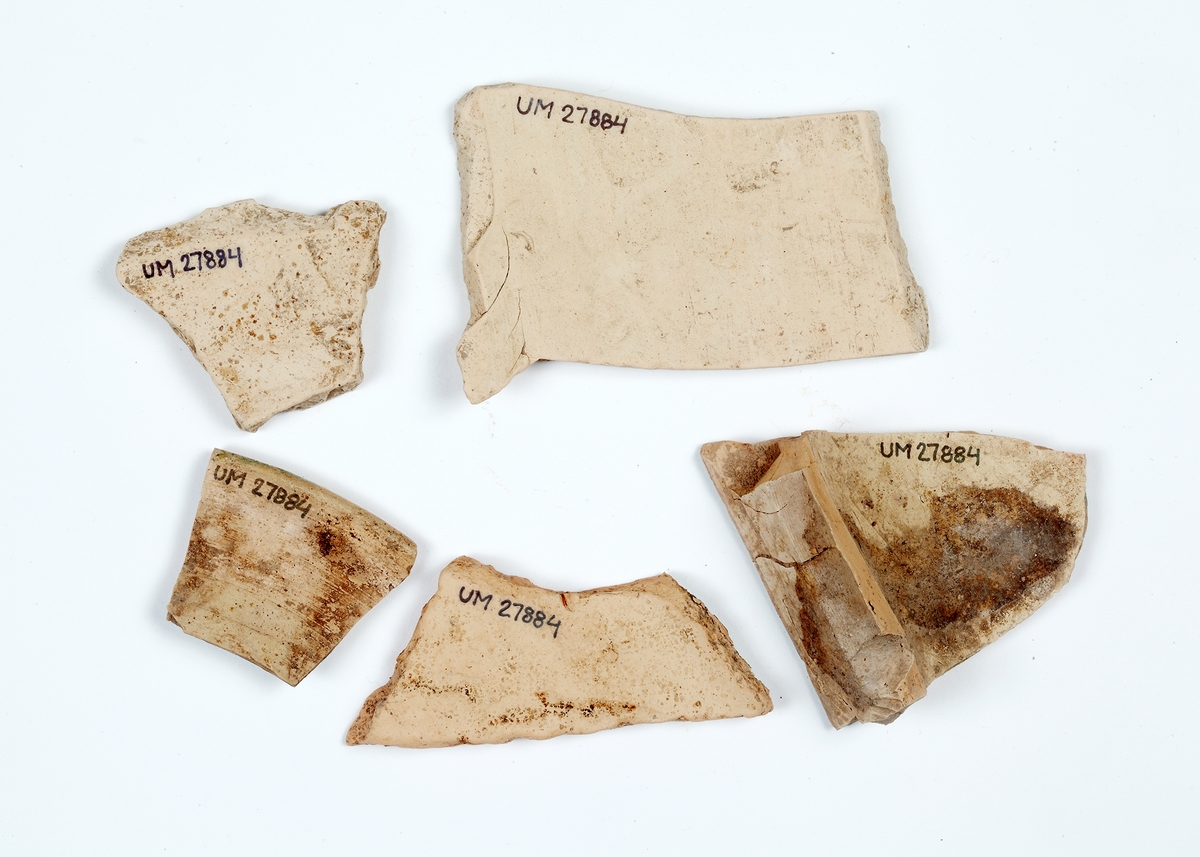 Delar av kärl. 10 stycken keramikfragment. Fyra brunglaserade bitar till mindre kärl, fem bitar grönglaserat lergods samt en vitglaserad bit med blå dekor.