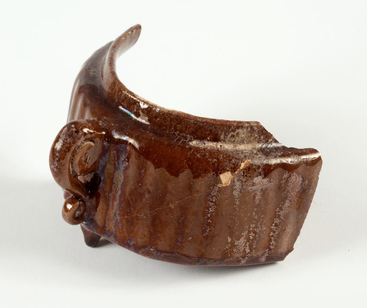 Delar av kärl. 10 stycken keramikfragment. Fyra brunglaserade bitar till mindre kärl, fem bitar grönglaserat lergods samt en vitglaserad bit med blå dekor.