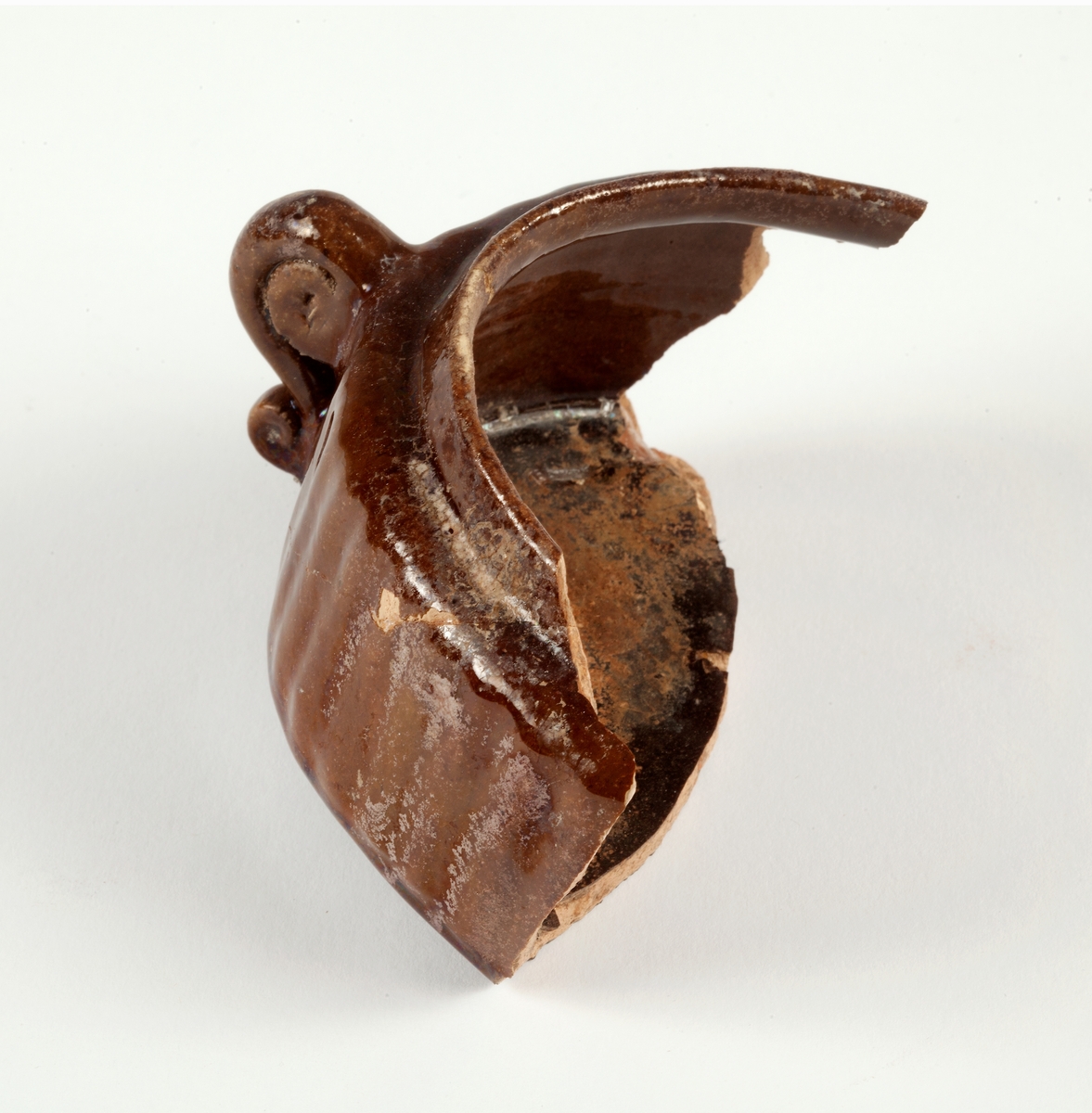 Delar av kärl. 10 stycken keramikfragment. Fyra brunglaserade bitar till mindre kärl, fem bitar grönglaserat lergods samt en vitglaserad bit med blå dekor.