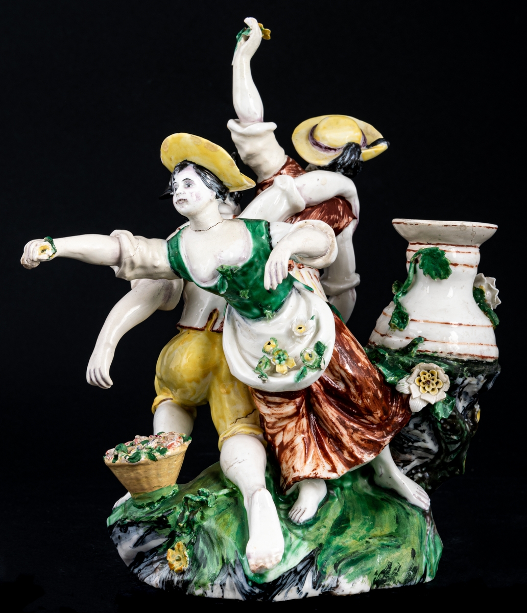 Figurgrupp. Herde och blomsterplockerskor, grupp av mjukt porslin.
Märke: MB - Marieberg. Berthevins tid 1766-1769, oläsligt, H. F. (tillverkad av Hierner?)

Gruppen består av en mansfigur och två kvinnofigurer samt en urna på en trädstam. Målat i polykromoa färger - grönt, brunt och gult.