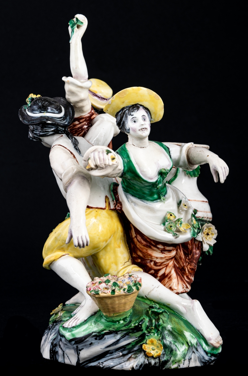 Figurgrupp. Herde och blomsterplockerskor, grupp av mjukt porslin.
Märke: MB - Marieberg. Berthevins tid 1766-1769, oläsligt, H. F. (tillverkad av Hierner?)

Gruppen består av en mansfigur och två kvinnofigurer samt en urna på en trädstam. Målat i polykromoa färger - grönt, brunt och gult.
