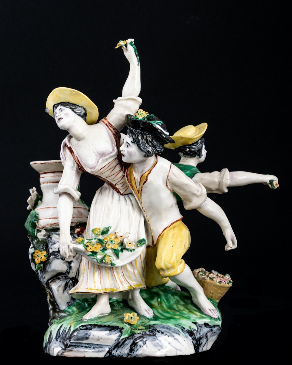 Figurgrupp. Herde och blomsterplockerskor, grupp av mjukt porslin.
Märke: MB - Marieberg. Berthevins tid 1766-1769, oläsligt, H. F. (tillverkad av Hierner?)

Gruppen består av en mansfigur och två kvinnofigurer samt en urna på en trädstam. Målat i polykromoa färger - grönt, brunt och gult.