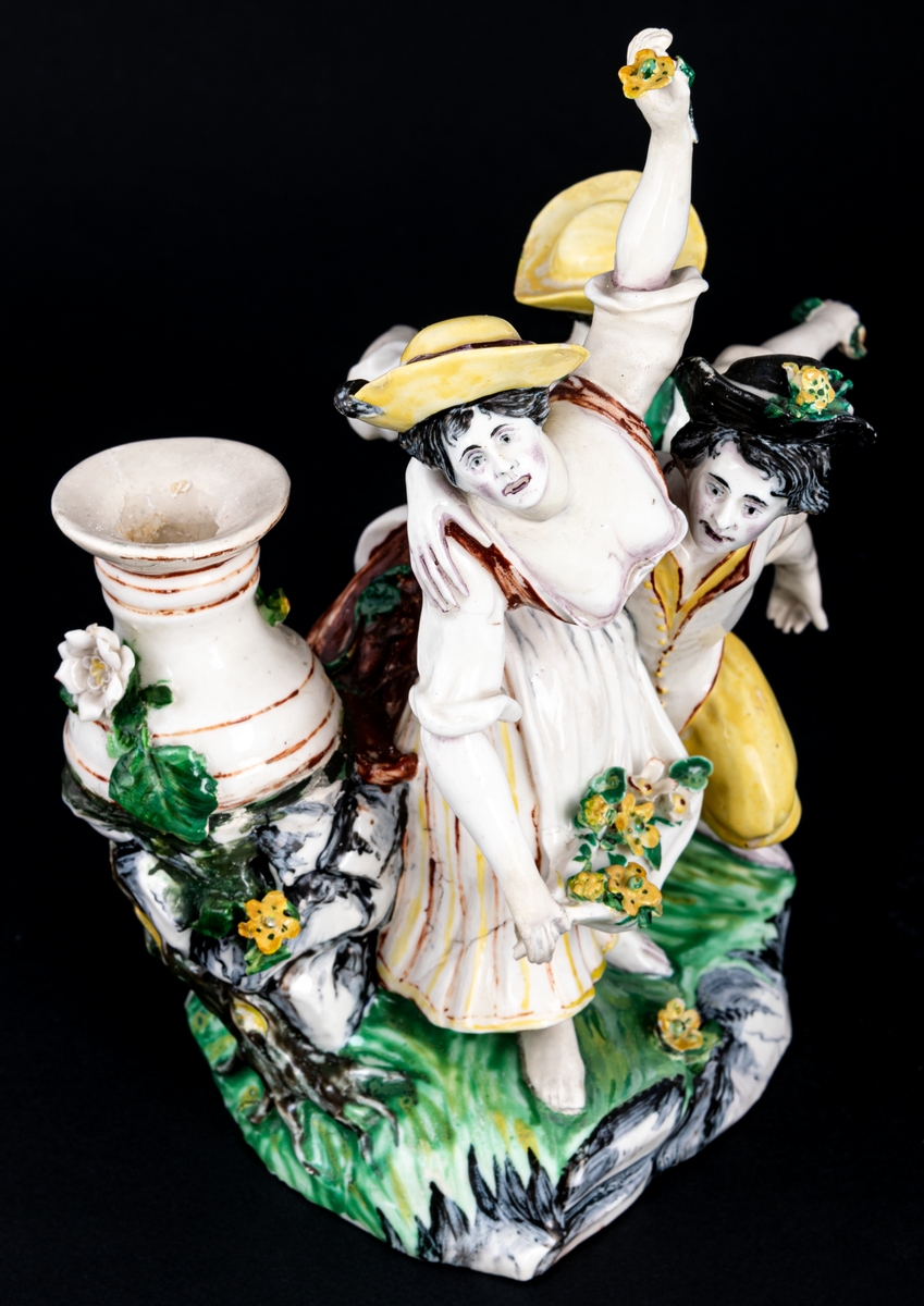 Figurgrupp. Herde och blomsterplockerskor, grupp av mjukt porslin.
Märke: MB - Marieberg. Berthevins tid 1766-1769, oläsligt, H. F. (tillverkad av Hierner?)

Gruppen består av en mansfigur och två kvinnofigurer samt en urna på en trädstam. Målat i polykromoa färger - grönt, brunt och gult.