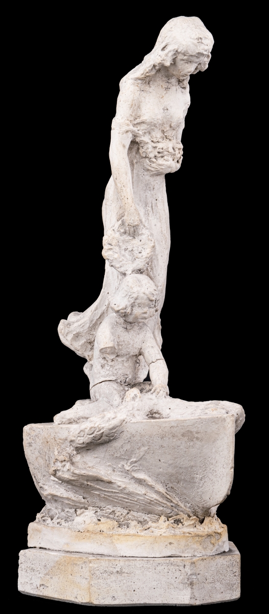 Skulpturskiss av Ida Matton, signerad Paris 1920, till gravmonument för redarfamiljen Brodin i Gävle. Kvinna med blommor i händerna med ett barn med blomgirlang sittande framför fötterna. Båda placerade på en trekantig sockel som liknar stäven på en båt.