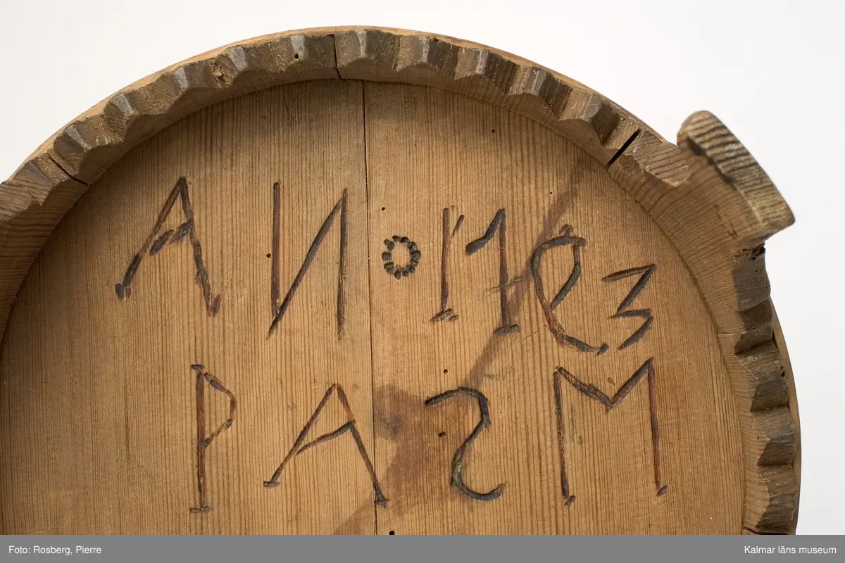 KLM 6425. Grötbytta. Av furu. Laggad, band av björkspån och vidja. Tre fötter. Ornering i form av inbrända punkter i geometriska mönster, cirklar. På lockets undersida inskuret: P A S M, i botten undersida: ANO 1793 P A S M. Omålad.