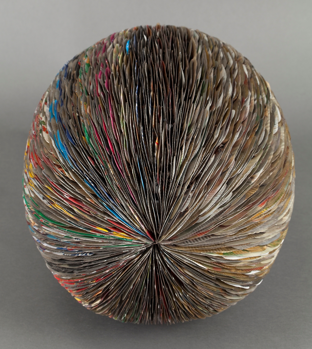 Eggformet skulptur, satt sammen av utallige tilskårede metallplater fra hermetikkbokser. Metallplatene er festet lag på lag rundt en akse og kan minne om formen til en kongle.