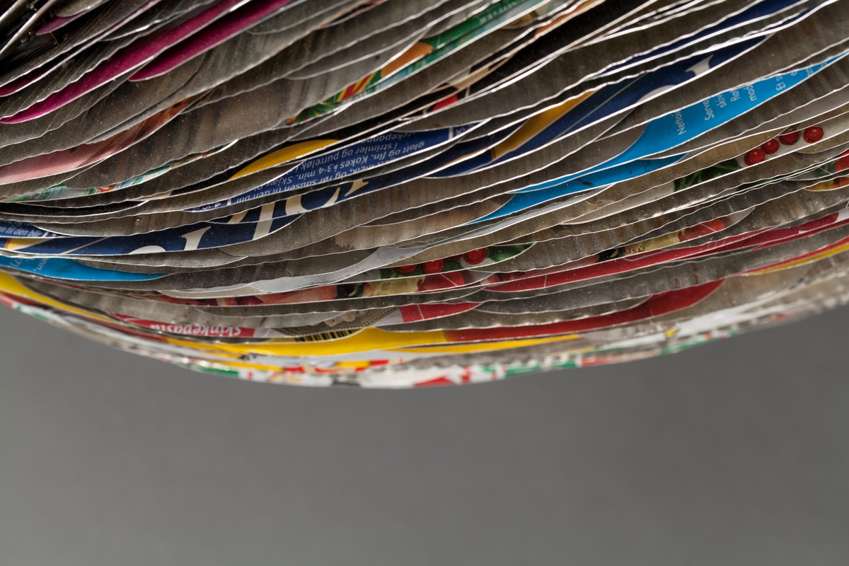 Eggformet skulptur, satt sammen av utallige tilskårede metallplater fra hermetikkbokser. Metallplatene er festet lag på lag rundt en akse og kan minne om formen til en kongle.