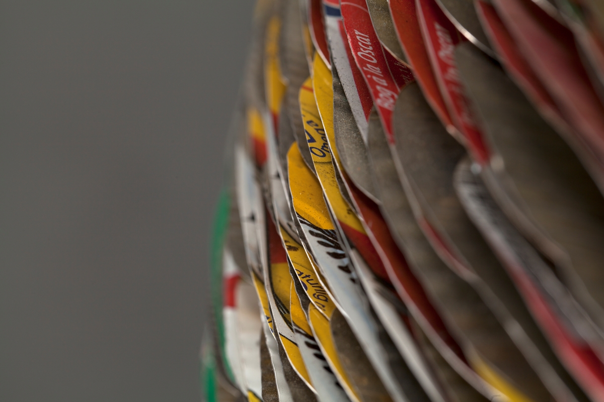 Eggformet skulptur, satt sammen av utallige tilskårede metallplater fra hermetikkbokser. Metallplatene er festet lag på lag rundt en akse og kan minne om formen til en kongle.