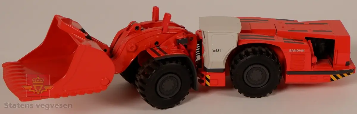 Sandvik LH621. Miniatyrmodell av en lastemaskin. Maskinen er produsert i metall med hjul av plast som er påsatt gummidekk. Modellen er rød med hvit hytte og har påskriftene SANDVIK og LH621. Innskriften conrad Made in Germany Scale 1:50 er preget inn i metallet på undersiden av maskinen.