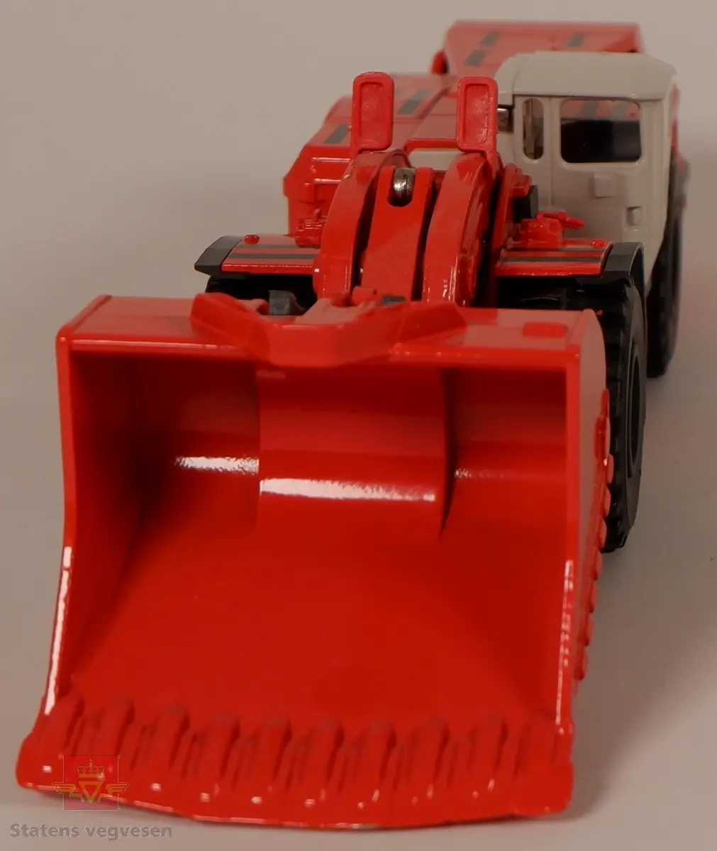 Sandvik LH621. Miniatyrmodell av en lastemaskin. Maskinen er produsert i metall med hjul av plast som er påsatt gummidekk. Modellen er rød med hvit hytte og har påskriftene SANDVIK og LH621. Innskriften conrad Made in Germany Scale 1:50 er preget inn i metallet på undersiden av maskinen.