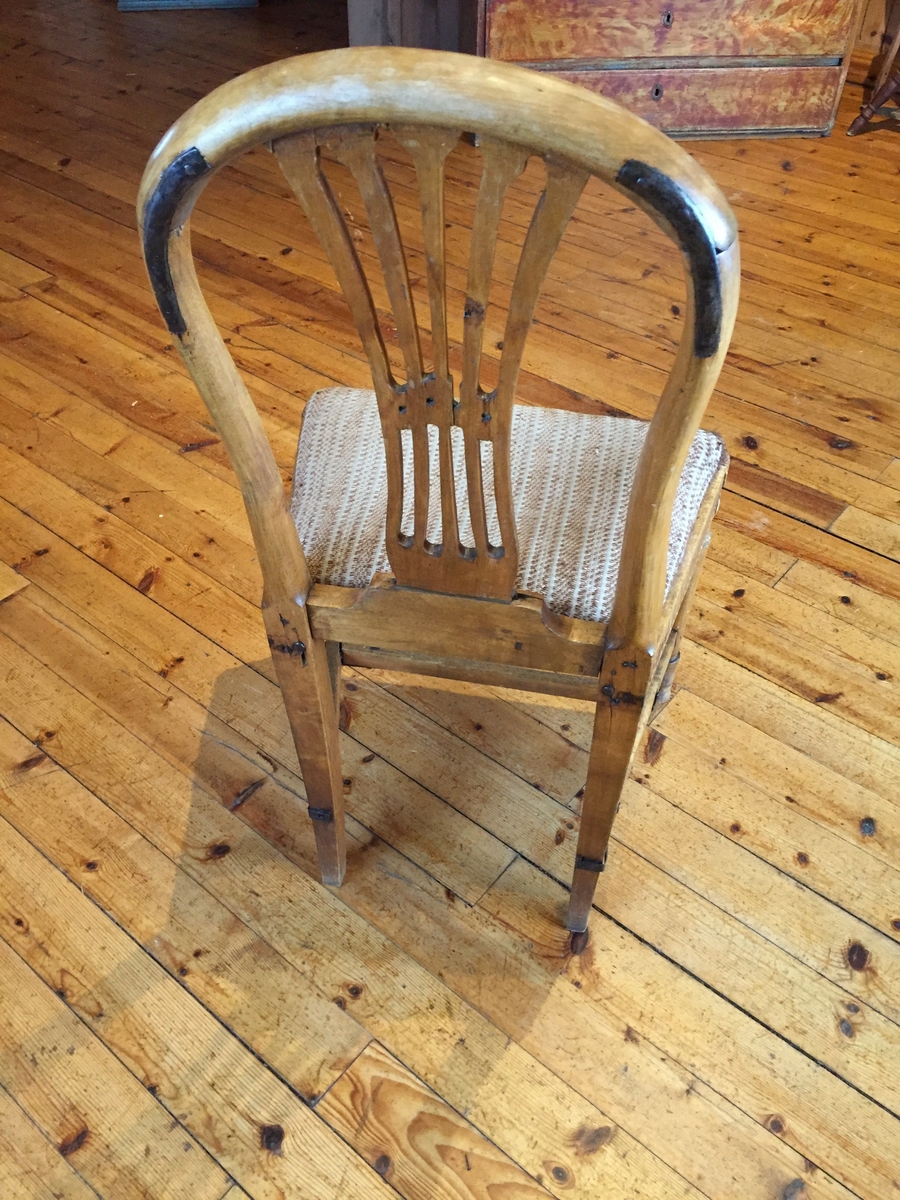 Stol med boga rygg. Spiler med utskjeringar i ryffen. Utskjeringar kring setet. Beina framme er dreia. Pute med heimevove trekk. Puta er laus. Det er eldre stoff (ullstoff) under det trekket som er på nå.