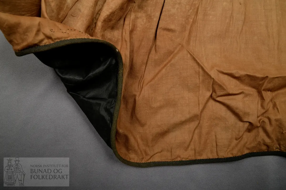 Brudeskjørt i svart silketaft, trolig brukt sammen med understakk NBF2021-0840.
Mørk grønt kypertvevd bånd påsydd for hånd rundt nedkant. 
Bomullsstoff , lerret til skoning.
Piperynket bak.
Splitt litt mot venstre side bak.