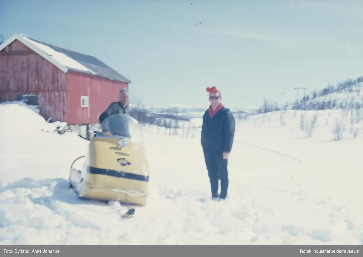 Olav og Johan Vågen står i snøen på gården Aust-Førnes, på Møsstrond. Olav ved snøskuter og rød låve i bakgrunn