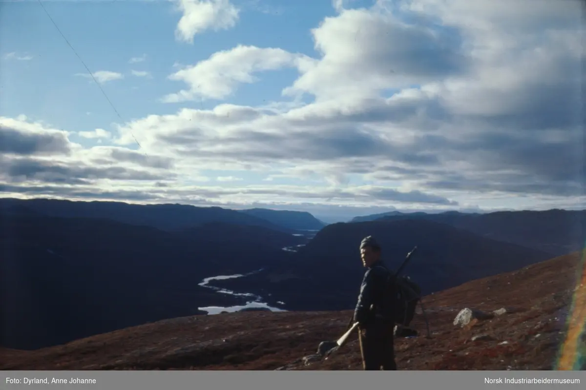 Bjørn Dyrland på jakt i fjellet. Står på fjellet med utsikt mot Argehovd og Kvenndalen