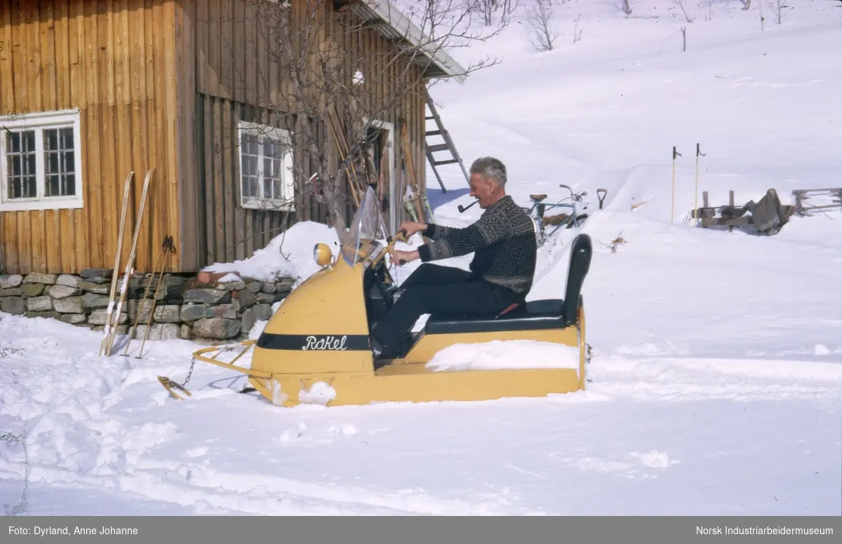 Olav Vågen med pipe i munn kjører snøskuteren "Rakel" i snøen på Aust-Førnes