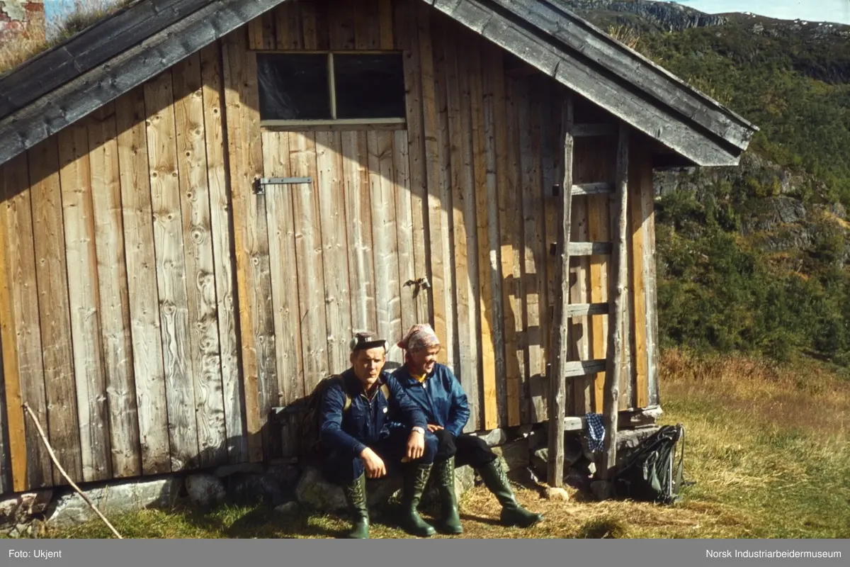 Anne og Bjørn Dyrland sitter inntil husvegg på Dalastaul gnr. 128/9 i Leirgrovdalen i Åmotsdal.