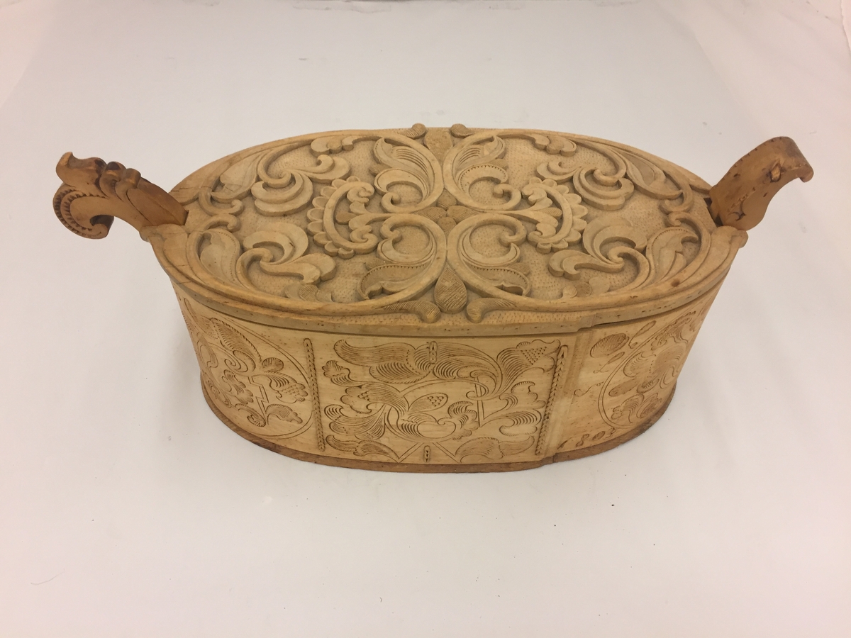 Sveipa, oval tine med utskjeringar. Flat, innrissa skurd på sjølve asken. Loket har også utskjeringar. C-krullar, blad, sirkelformer m.m. Bokstavane  (?) L S 1803 er skore inn. Eit "øyre" på kvar side av tina.