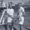 Tennisfinaler och prisutdelning en måndag. Två tennisspelare skakar hand. En pojke vid domarplatsen till vänster.