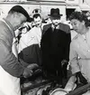 Albert Johansson, fiskhandlare i Ingemanssons fiskaffär, Växjö, servar kunder på Stortorget i Växjö 1962.
I bakgrunden skymtar Skånska bankens fastighet vid Kungsgatan.