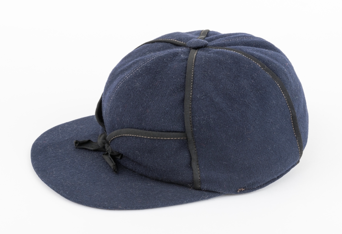 Lua er ei østerdalslue av den modellen som Olai Pedersen lanserte i 1906.  Den er sydd av mørkeblå vadmel og kantete med svart stoff.  På innsida av øreklaffene er det brunt skinn. 