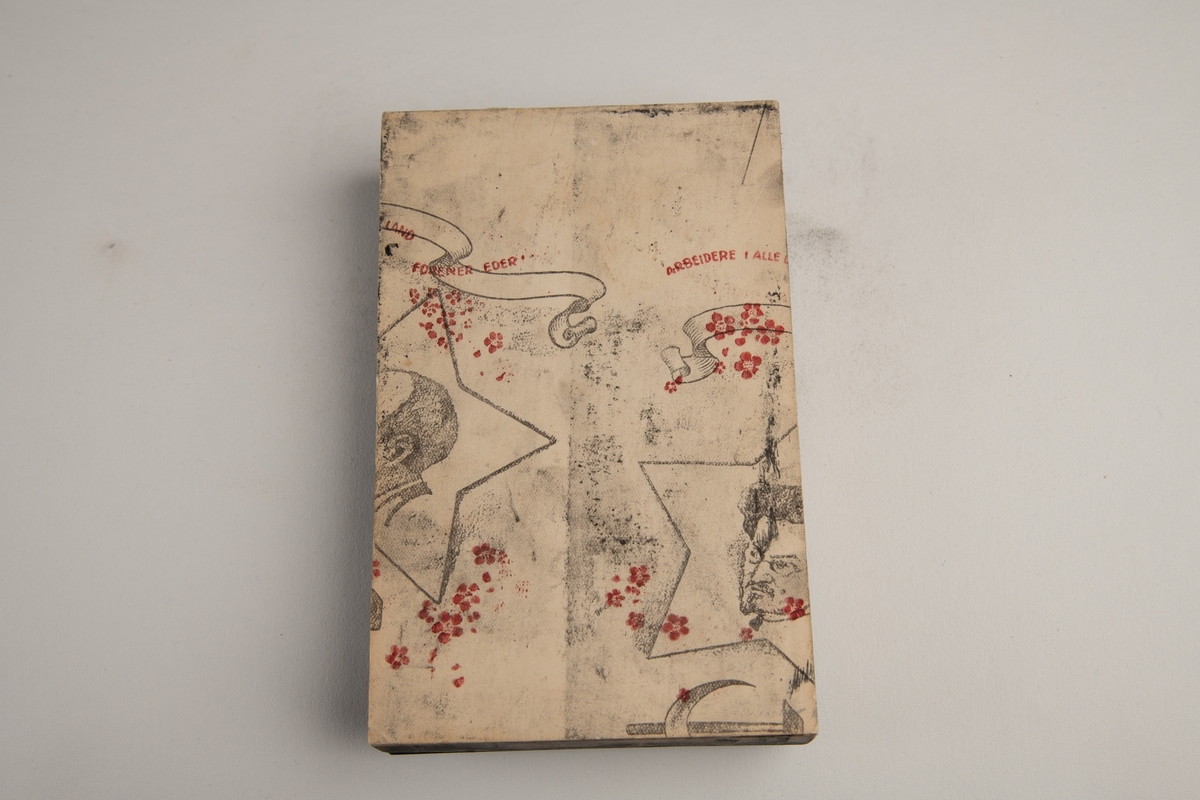 På metallplaten: Et ganske slitt bymotiv. Tett trehusbebyggelse og bygater. På papiret på baksiden: Et utsnitt av et større verk. Halvparten av en stjerne med et hode inn og et banner over, på venstre side, og tilsvarende på høyre. Vi kan se en del av noe som må være et hammer og sigd-motiv.