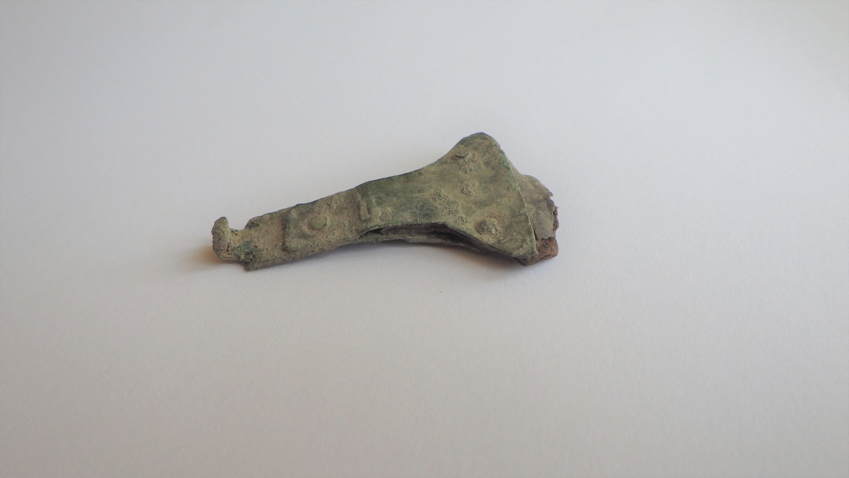 MALV: L. 4, 5 CM  B. 3, 0 CM, TO SAMMENNITEDE REKTANGUL’RE BRONSEPLATER. DEN ENEENDEN ER UTFORMET SOM EN KROK, DENN ANDRE ENDEN UTVIDER SEG OG DANNERFESTE FOR L’RREMMEN SOM ER FESTET MELLOM BRONSEPLATENE. 