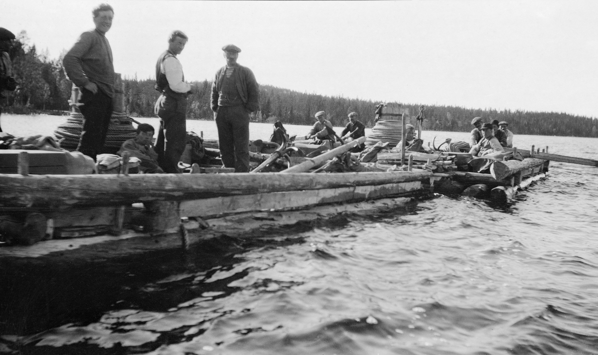 Nordlaget på Osensjøen, fotografert i arbeid på spillflåter under fløtinga i 1919. Bildet viser to flåter som lå inntil hverandre. På den nærmeste sto tre menn oppreist, mens det kan synes som om en fjerdemann lå med hodet inntil trossa på tønna (gangspillets vertikala akse). På den andre flåten satt seks-sju menn ved årene. Tønna var full av trossetau og dreggen (ankeret) lå på flåten.