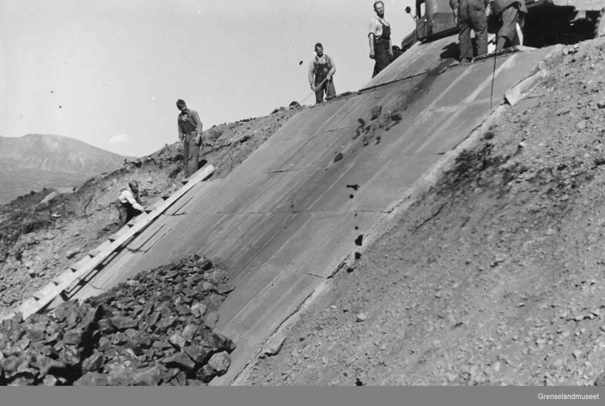 Menn i arbeid med tipping av malm ved utskipingskaia i Burfjord august 1937.