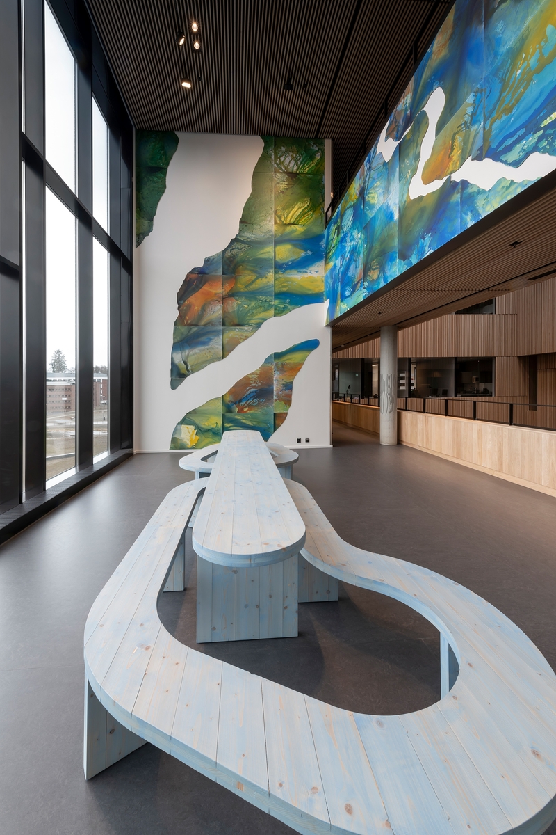 Kunstneren inntar rommets tre vegger med et monumentalt maleri. På gulvet står tremøblet The Loop. Det åpne rommet går i dialog med arkitekturen innover i bygningen og med utsikten over parken. Kunstverket er synlig fra utsiden, akkurat som veggmaleriet til Anders Smebye på Veterinærinstituttet, og begge verkene deler de tematiske berøringspunktene vann og økologi. De landskapslignende formene i maleriet er arbeidet frem vått i vått på liggende plater til en organisk og flytende helhet. De to benkene bukter seg gjentakende rundt bordet som ringer i vann.

Bakgrunnen for kunstverket er kunstnerens opplevelse av familiens oversvømte risåkrer i hjemlandet Thailand, en erfaring hun stadig bruker som utgangspunkt i sin kunst. Maleriet er en personlig refleksjon over et alvorlig tema: lokale konsekvenser av klimaendringer og verdenssamfunnets ansvar for og håndtering av naturkatastrofer.

The Loop er laget i samarbeid med arkitekt Cristian Stefanescu.