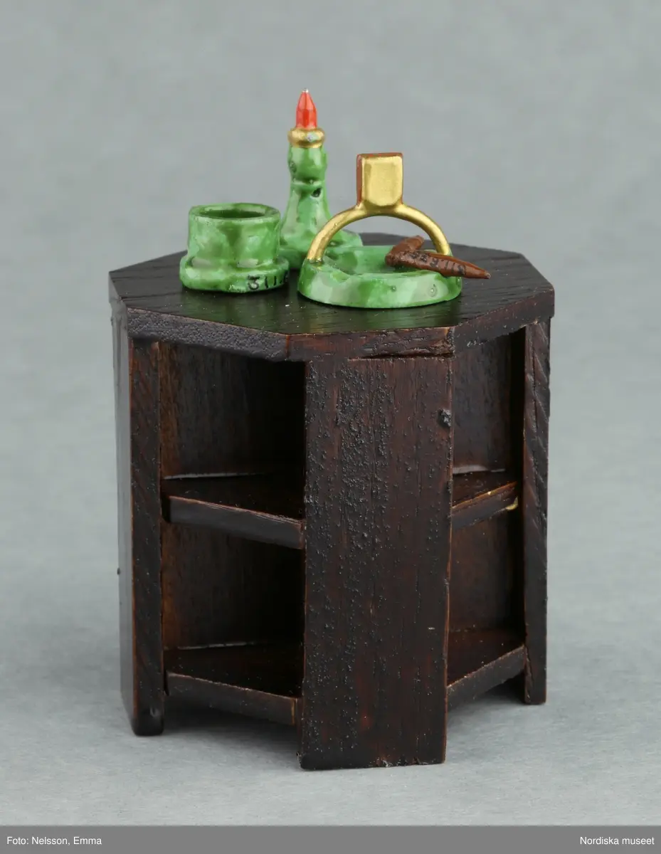 Inventering Sesam 1996-1999:
B 77,5, Djup 36,0, H 119,0 cm
Dockskåp av furu med mellanväggar av plywood, målat i gräddgult, fasaden "putsad" med färg blandad med sågspån. Dockskåpet har dubbeldörrar med lås och en fasad på gångjärn med en dörr och 10 fönster, inspirerad av det första kollektivhuset i funkisstil på John Erikssons gata. Dockskåpet är befolkat av fam. Björnerholm. Gunvor Svartz-Malmberg f. 1925-6 var ca 10 år när hon fick skåpet. 
LS 85
Helena Carlsson