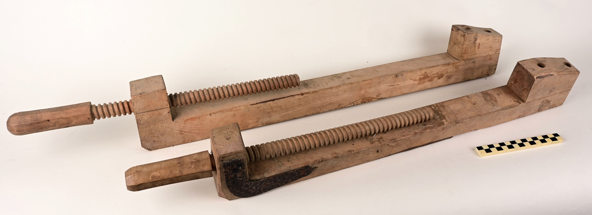 Tvinger bestående av treskrue med håndtak, og lengdestykke med oppstikkende motstykke som skal holde emnet på plass.. Tvingene er litt ulike i lengde. Den minste er forsterket med to stålbeslag på hver side av trestykket som skruen går gjennom. Motstykket er klinket fast med båtnagle i stål.