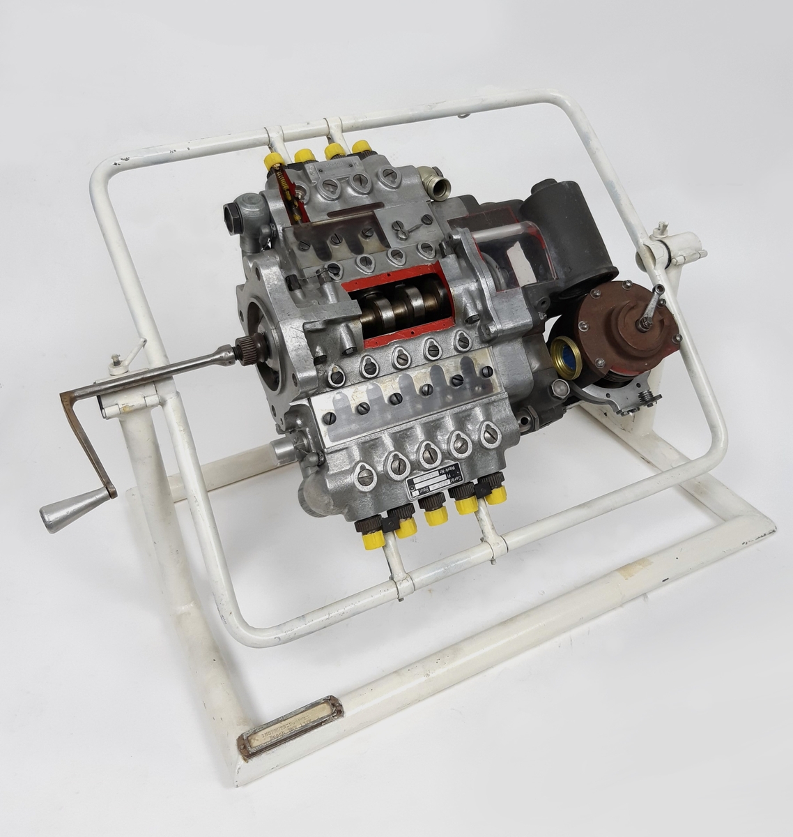 Insprutningspump, Bosch till stjärnmotor BMW 132K, monterad på ett vitt stativ i metall. Uppskuren för undervisning. Tillverkare: Bosch, Germany.