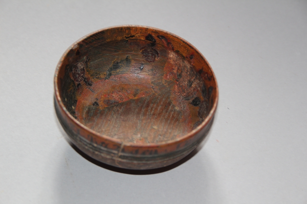 Liten dreia bolle. Rosemåla med tekst kring kanten på utsida. Teksten er utydleg men det kan lesast "R.O.S.1775 sett(?) nu mig bie(?) snart får du rusen føle" Rosemåling inni bollen, blad og blomstermotiv. Rosemålinga er noko slitt. Utanpå er bollen brunmåla, med ei grøn stripe og orange kant. Bollen har ein skade på den eine sida. denne skaden er lima.
