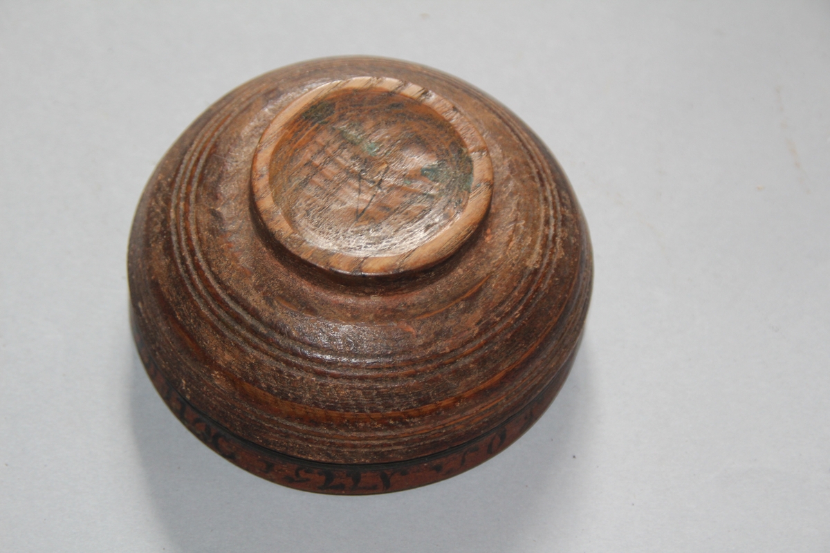 Liten dreia bolle. Rosemåla med tekst kring kanten på utsida. Teksten er utydleg men det kan lesast "R.O.S.1775 sett(?) nu mig bie(?) snart får du rusen føle" Rosemåling inni bollen, blad og blomstermotiv. Rosemålinga er noko slitt. Utanpå er bollen brunmåla, med ei grøn stripe og orange kant. Bollen har ein skade på den eine sida. denne skaden er lima.